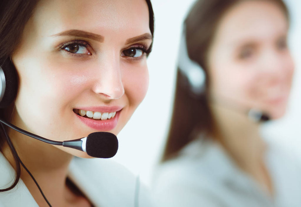 Mujer de negocios sonriente u operador de línea de ayuda con auriculares y computadora en la oficina - Foto, Imagen