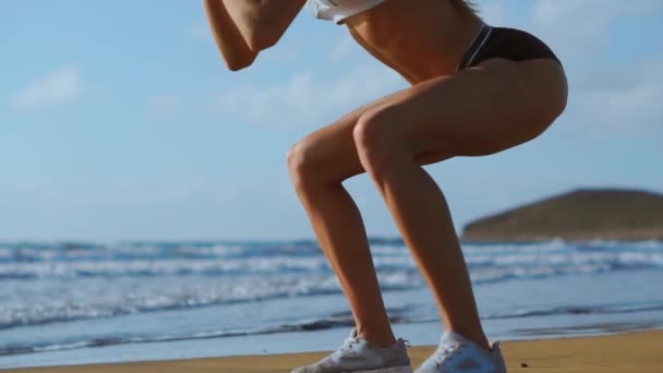 Fitness nuori nainen treenaa ydin ja glutes kanssa kehon paino workout tekee kyykky harjoituksia rannalla. urheilullinen tyttö kyykyssä jalat osana aktiivista ja kunnossa elämää. Höyrypuut
 - Materiaali, video