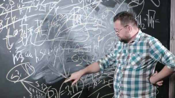 Un matemático maduro brillante trae un tablero grande y completa un ensayo ecuación matemática complicada de la fórmula
 - Metraje, vídeo