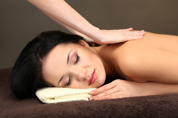 Beautiful young woman in spa salon getting massage, on dark background - Photo, Image