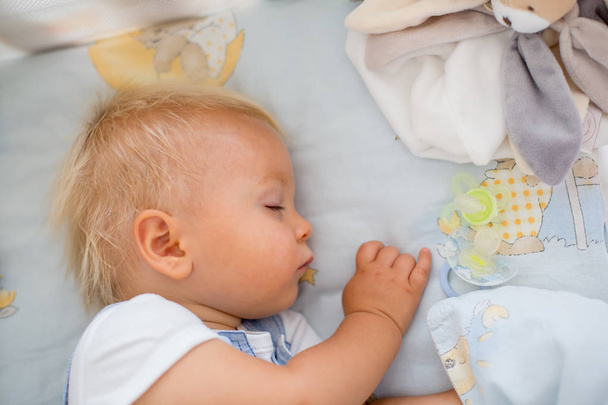 Маленький хлопчик спить у дитячому ліжку з соску поблизу
 - Фото, зображення