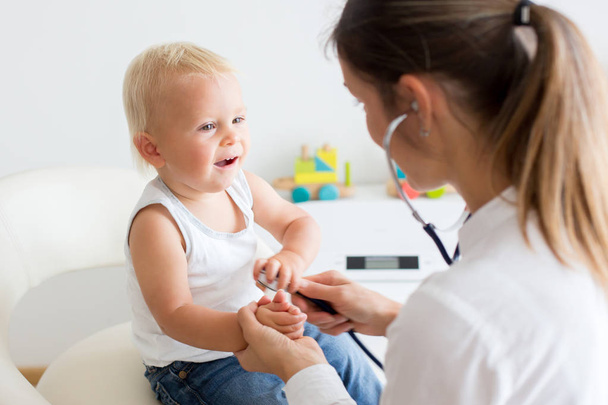 Çocuk doktoru, bebeğini muayene ediyor. Doktor steteskop kullanarak çocuğu dinliyor ve kalp atışlarını kontrol ediyor. - Fotoğraf, Görsel