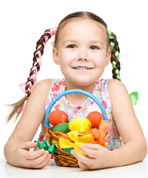 Little girl with basket full of colorful eggs - Foto, afbeelding
