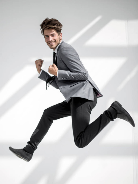homem de negócios pulando e sorrindo para a câmera, sobre backgr branco
 - Foto, Imagem