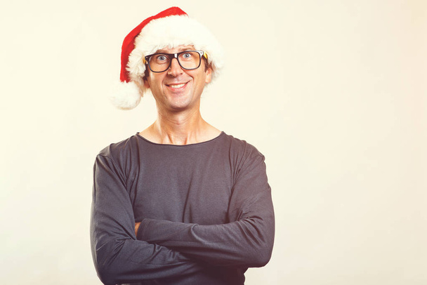 Усміхнений чоловік в окулярах носить Санта-капелюх. З Новим роком. Різдвяний час. Забавна людина в різдвяному капелюсі, ізольована на білому. Копіювати простір. Різдвяний настрій. Люди, різдво, продажі та концепція способу життя
 - Фото, зображення