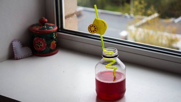 μπουκάλι με χυμό κοντά στο παράθυρο - Φωτογραφία, εικόνα