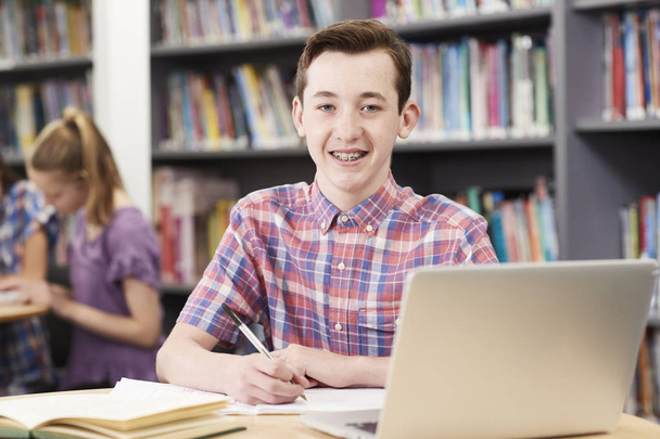 Férfi középiskolás diák dolgozik a Laptop-ban könyvtár portréja - Fotó, kép