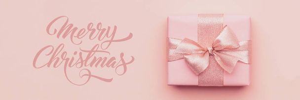 Christmas banner. Beautiful pink christmas gift isolated on pastel pink paper background.  - Zdjęcie, obraz