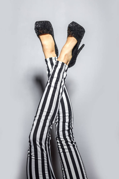 Woman legs wearing high heels and striped pants - 写真・画像