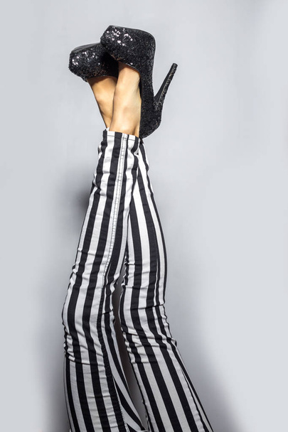 Woman legs wearing high heels and striped pants - Zdjęcie, obraz