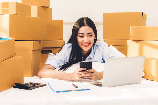Jeune femme pigiste travaillant et utilisant un ordinateur portable avec boîte en carton sur le lit à la maison - PME entreprise en ligne et concept de livraison
 - Photo, image