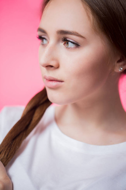 Sideways close up portrait of young girl on a pink background - Photo, Image