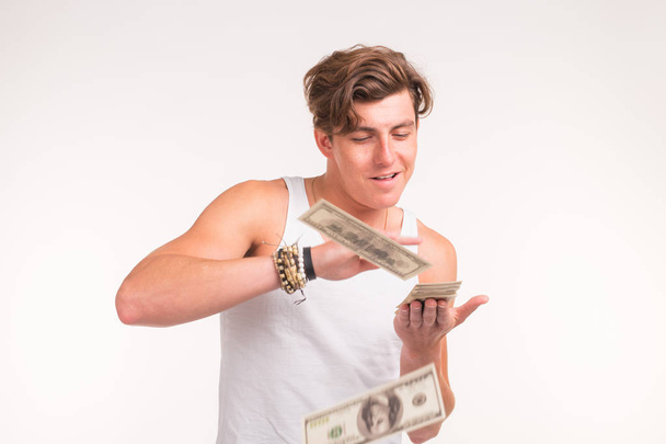 reich, lustig und Finanzkonzept - schöner junger Mann wirft Geld über weißen Hintergrund. - Foto, Bild