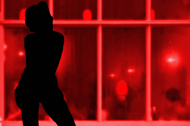 Sexy young girl silhouette standing in front of a red window hooker concept - Photo, Image