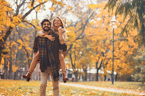 Молода усміхнена пара насолоджується падінням в парку
. - Фото, зображення