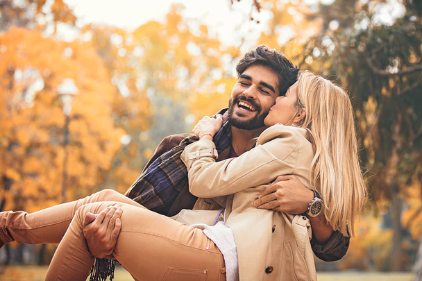 Young smiling couple enjoying fall in the park. - Фото, изображение