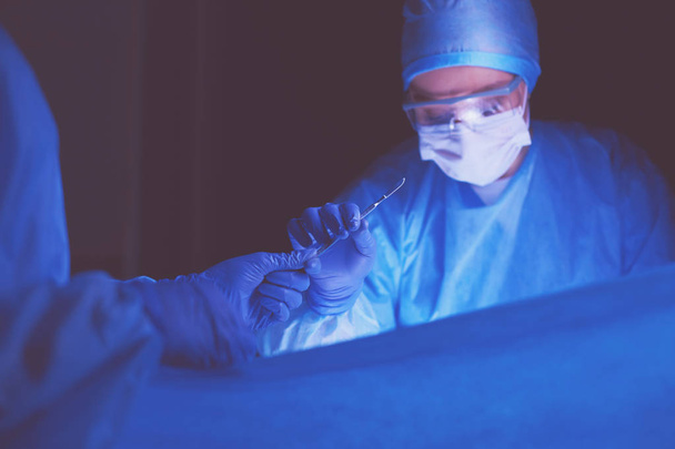 Doctor performing surgery in a dark background. - Foto, Imagem