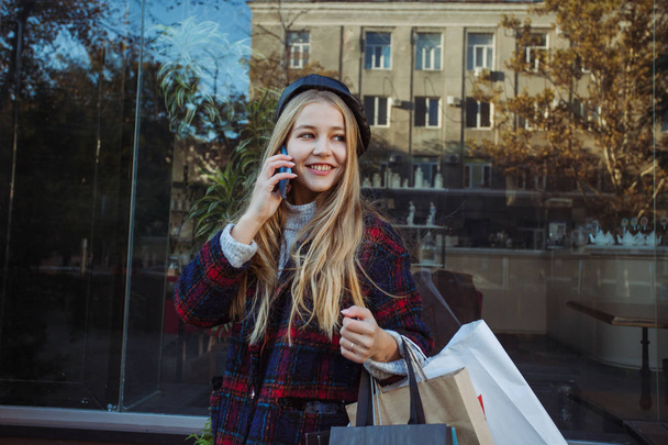 Happy woman talking by smartphone and holding shopping bags - Fotoğraf, Görsel