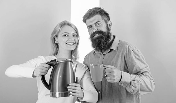 Man with mug and woman with electric kettle ready to drink morning coffee. First thing they do every morning prepare hot drink. Get energy charge favourite hot drink. Enjoying nice morning together - Zdjęcie, obraz