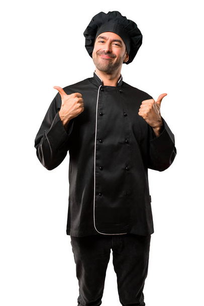 Άνδρας σεφ στην μαύρη στολή δίνοντας ένα μπράβο χειρονομία με τα δύο χέρια και να χαμογελά. Χαρούμενη έκφραση στο απομονωμένο λευκό φόντο - Φωτογραφία, εικόνα