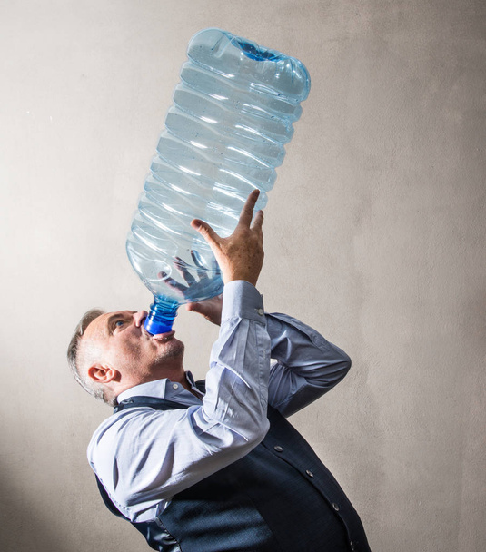 een man met een gigantische waterfles - Foto, afbeelding