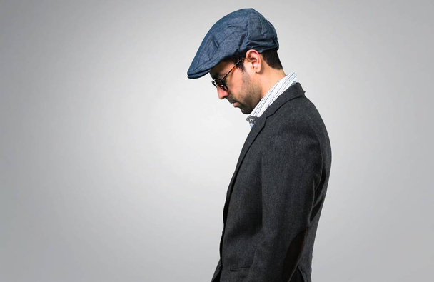 Hombre moderno guapo con boina y gafas en posición lateral sobre fondo gris
 - Foto, imagen