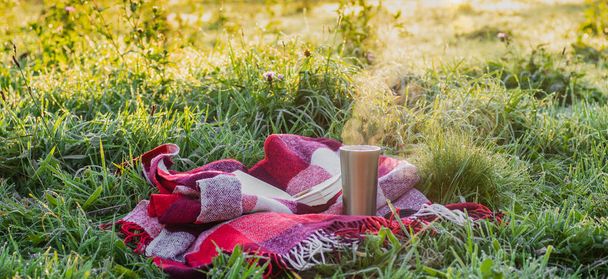Открытая книга в саду, книга, термос с чаем, пар над термостатом. Теплое одеяло. Открытая книга о природе. Книга
  - Фото, изображение