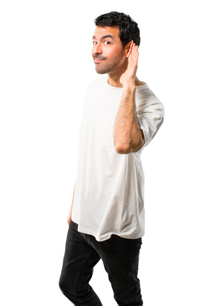 Młody człowiek z białą koszulę, słuchając coś kładąc rękę na ucho, na białym tle - Zdjęcie, obraz