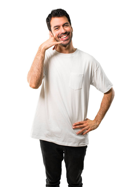 Young man with white shirt making phone gesture and speaking with someone. Call me back sign on isolated white background - Fotó, kép
