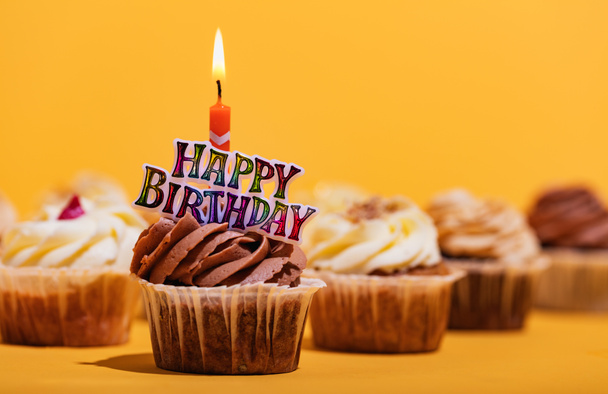 Cupcakes sobre fondo amarillo con vela de feliz cumpleaños. Deliciosas golosinas
. - Foto, imagen