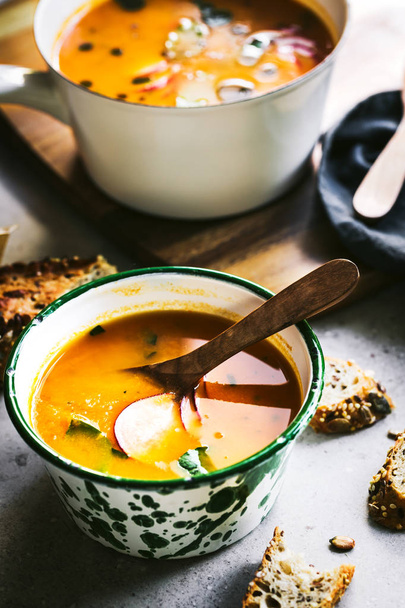 Sopa de cenoura e abóbora com óleo de manjericão por pão de sementes Multigrain
 - Foto, Imagem