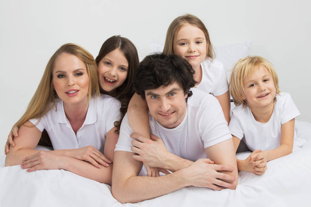 Family of parents and three children in white clothes laying on white background - Photo, Image
