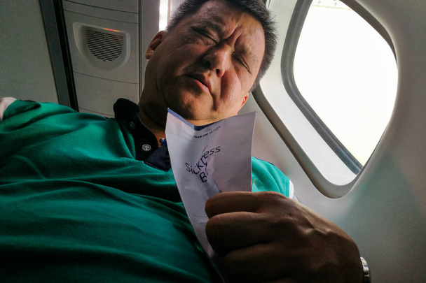 Страждання азіатських людині проведення нудота блювота подушки в кабіни літака - Фото, зображення