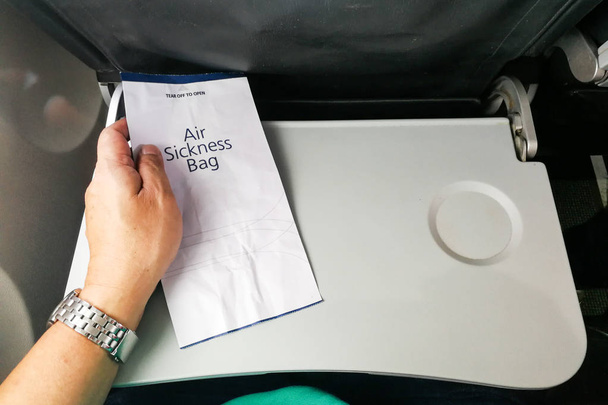 Pasajero sosteniendo la bolsa de vómito por enfermedad del aire en el avión para emergencias
 - Foto, imagen