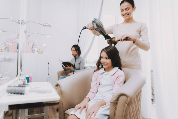Girl in Beauty Salon. Hairdresser Dries Hair. Little Lady in Chair. Consept Beauty Salon. Child in Beauty Salon. Beautiful Little Lady. Hairdresser Does New Styling. Hairdresser with Blow Dryer. - Fotó, kép