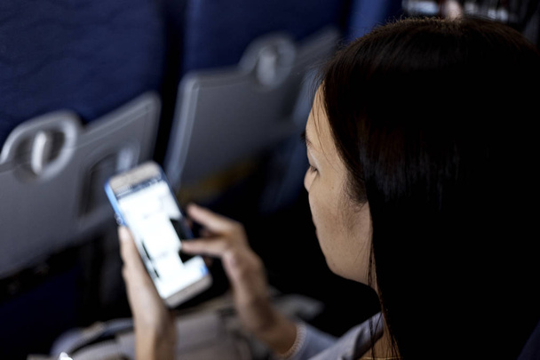 Genç kadın Asya Uçak, dünya seyahat kavramı, gece lambası smartphone kullanarak - Fotoğraf, Görsel