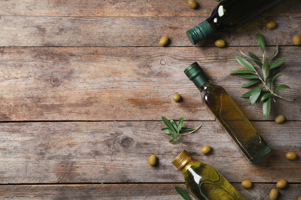Flat lay composition with bottles of olive oil and space for text on wooden background - Foto, Imagem