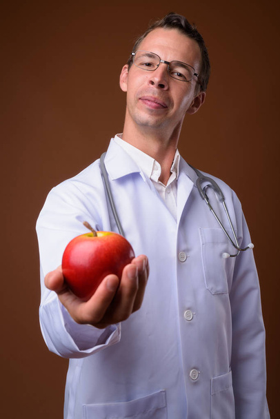 Studio shot of man doctor against brown background - Photo, Image