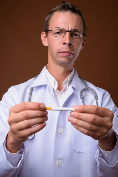 Studioaufnahme eines Arztes vor braunem Hintergrund - Foto, Bild
