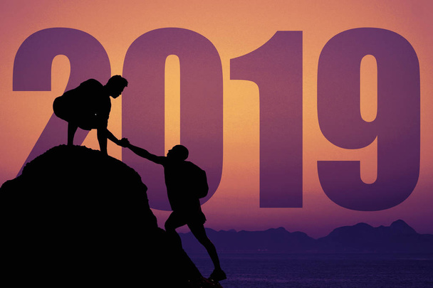 Силует двох альпіністів на вершині гори з новим 2019 роком як символ командної роботи та збагачення
 - Фото, зображення