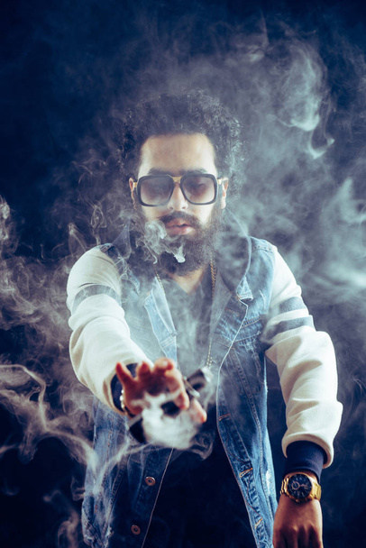 Vape κάπνισμα. vaping άνθρωπος που κρατά ένα mod. Vape δαχτυλίδια. Ένας άντρας ξεκινά ένα δαχτυλίδι του καπνού. - Φωτογραφία, εικόνα