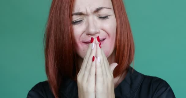 Disappointed and sad red haired woman with removing of makeup face hiding face by hands and crying and looking at camera. Green studio background. Concept of bad emotions and stress. - Footage, Video