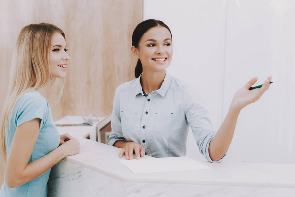 Woman Receptionist. Reception Workplace. Workplace in Beauty Salon. White Interior. White Reception Desk. Beauty Consept. Smiling Salon Employee. Customer Registration. Womans at White Reception. - Photo, Image