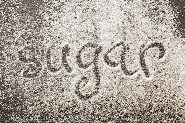 The word sugar written into a pile of white granulated sugar - Φωτογραφία, εικόνα