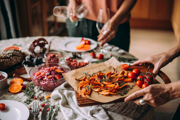 Friends serving dinner table, celebrating Christmas or New Year eve. Healthy modern vegetable dishes - 写真・画像