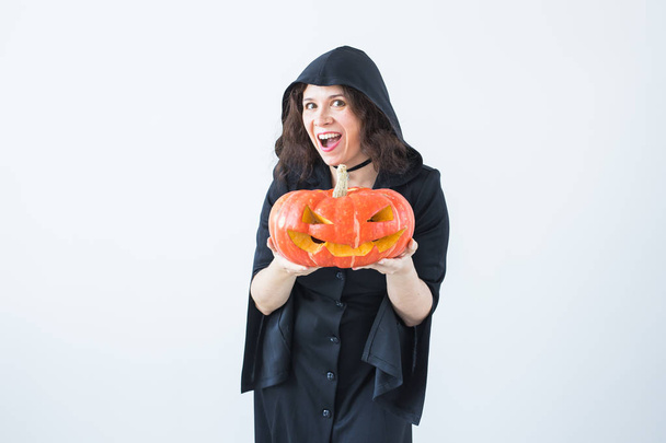 Halloween en maskerade concept - grappige jonge vrouw met pompoen Jack-o-lantaarn. - Foto, afbeelding