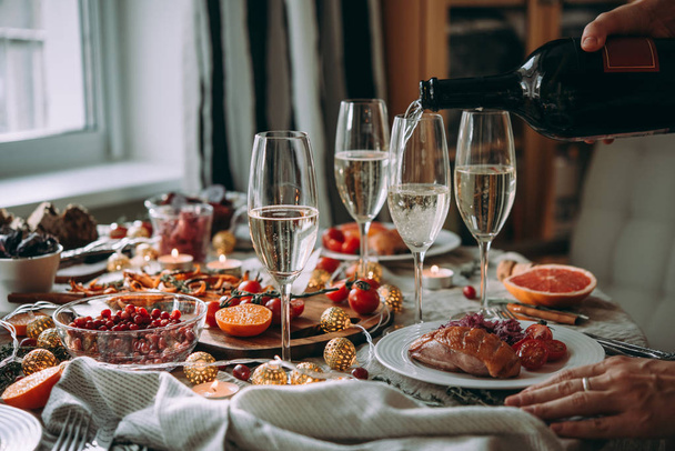Pouring wine at a dinner party with friends. Friends celebrating Christmas or New Year eve. - Foto, Imagen