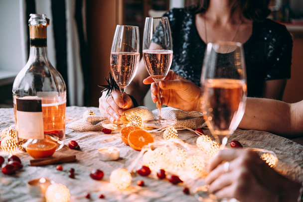 Friends celebrating Christmas or New Year eve. Party table with rose champagne. - Foto, Bild