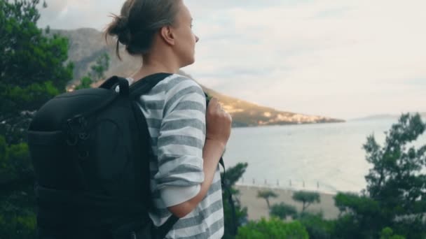 Žena s batohem poblíž pobřeží moře. - Záběry, video