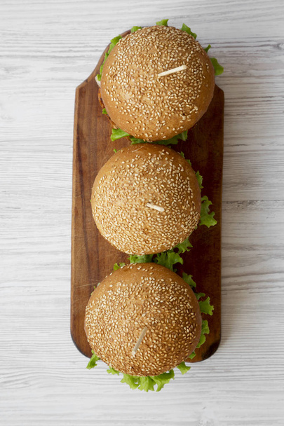 Cheeseburgers op houten bord over witte houten achtergrond, bekijken van bovenaf. Closeup. - Foto, afbeelding